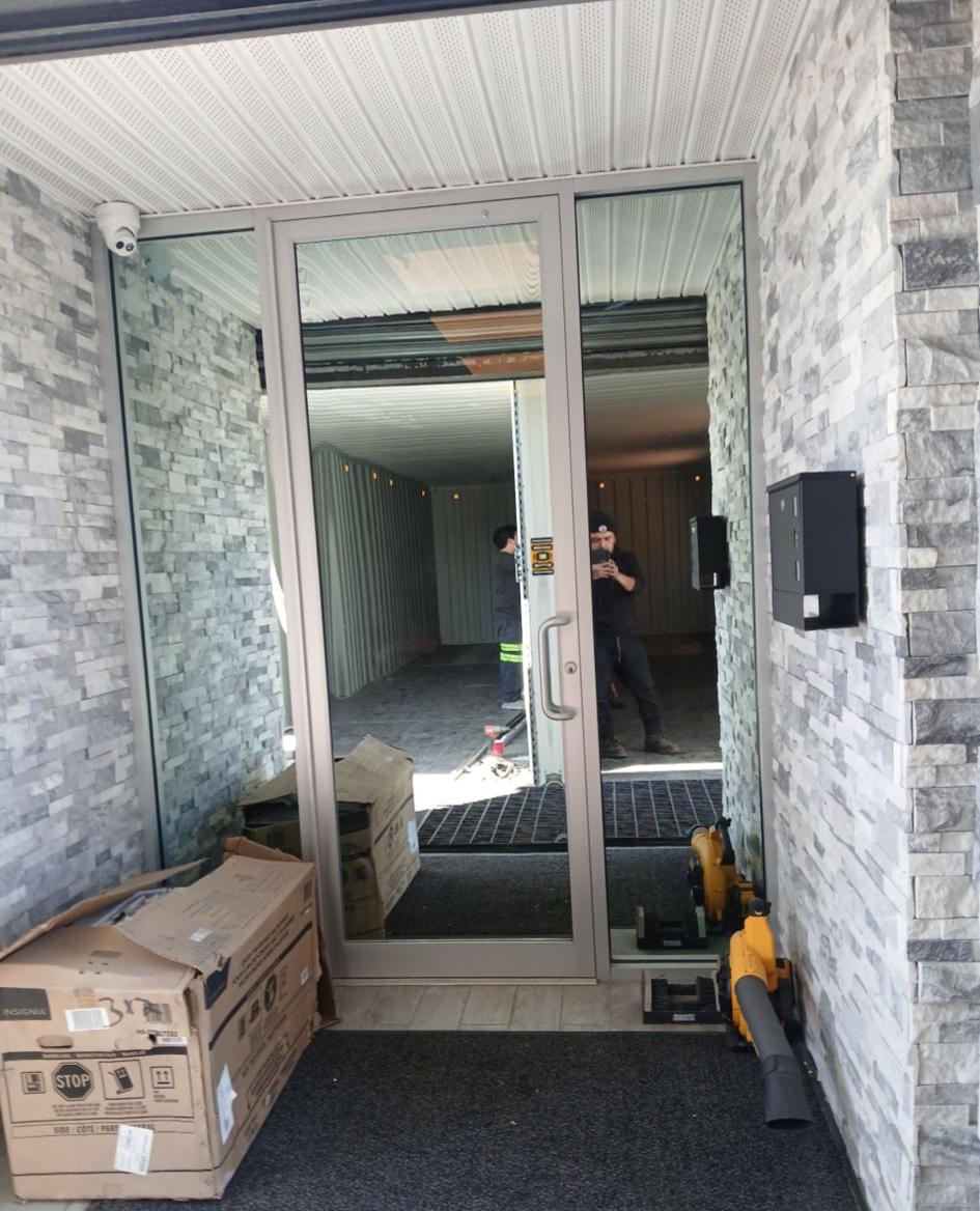 Commercial glass entrance door with stone veneer walls and silver aluminum frame